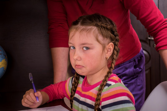 Sad Child Is Tired Of School Assignments. Mom Helps Her Daughter Do Her Homework. The Concept Of Home Education In Quarantine. A Little Girl Doesn't Want To Learn Lessons.