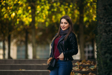 Stylish beautiful lady in a black leather jacket with a black bag and burgundy blouse