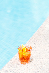 Negroni cocktail near a pool at the resort bar or suite patio. Luxury resort, vacation, holiday, getaway, summer time, room service concept. Vertical with place for text