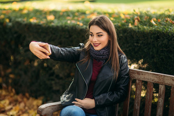 Stylish beautiful lady in a black leather jacket with a black bag and burgundy blouse. Attractive...