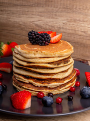 A stack of home-made pancakes with strawberries and blueberries