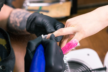 Close-up of hardware milling cutter for removing gel polish. Apparatus manicure in beauty salon. Manicurist with electric nail drill remove old gel from client nails. Process of replacing old shellac.