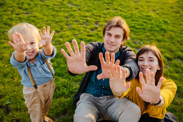 Loving family of father, mother and cute little son playing, counting, talking, studing while sitiing on grass together outdoor. Family connection, parenthood, love and tender moments concept.