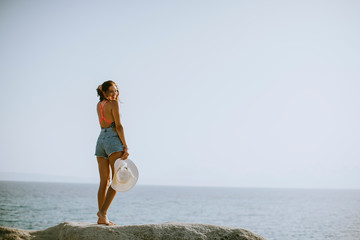 Young woman in bikini standing on rocks by the sea