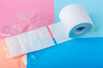 White toilet paper roll and disposable plastic gloves on colored background. Copy space for text, flat lay. Hygiene products. Protection during the coronavirus epidemic.