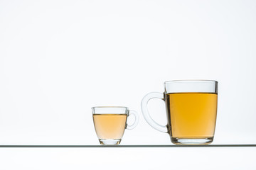 glass teapot and cups with hot tea on table, close view    