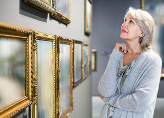 Female visitor looking at artwork painting in the museum indoors