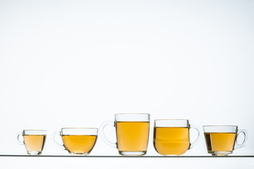 glass teapot and cups with hot tea on table, close view    