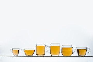 glass teapot and cups with hot tea on table, close view    