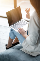 Naklejka premium Girl is an online conference on a laptop and waving to all participants in a white jacket sitting in a chair
