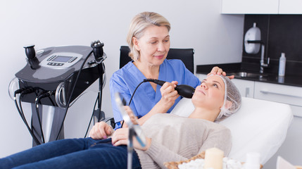 Cosmetologist performing machine facial procedure