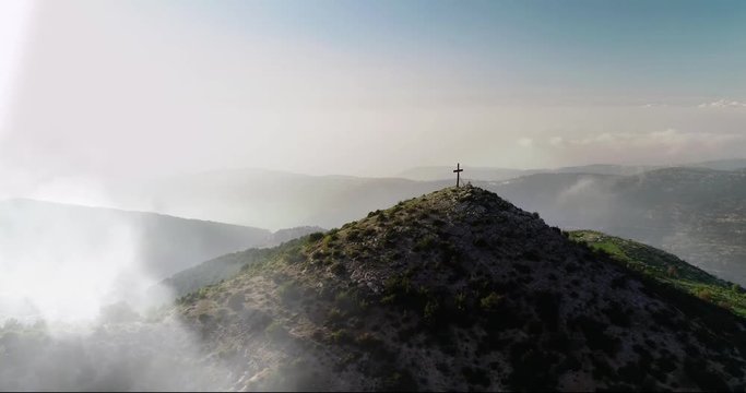 aerial circle shot between fog in green ranges of high landmark holy cross,  Ehden reserve