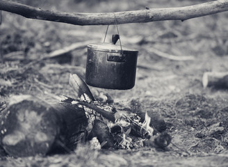 Outdoor cooking in old sooty cauldron on campfire