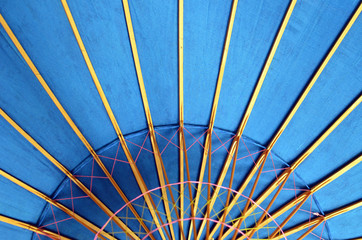 Fragment of a bright blue vietnamese traditional umbrella with wooden ribs. Symmetrical composition.