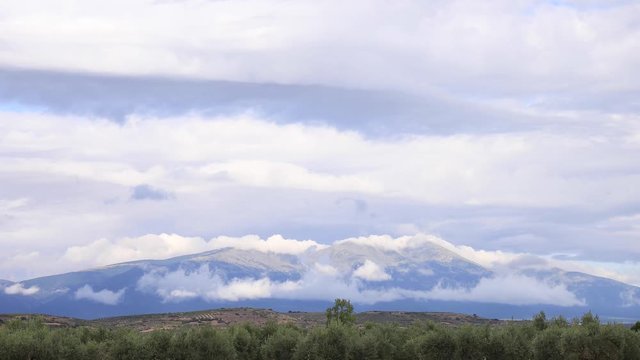 4k time lapse clouds passing over a spanish mountain, Moncayo, over a field of olive trees