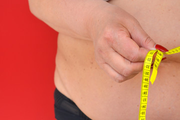 Woman measures a fat belly. Healthy lifestyles concept. Background to obesity