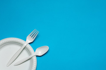 disposable plate, spoon and fork, made of corn starch on a blue background. biodegradable eco friendly picnic tableware. isolate. replacement of plastic with modern biomaterials.