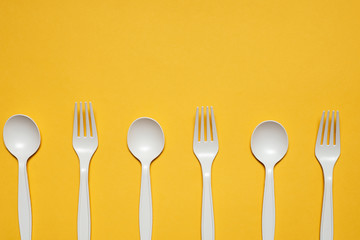 disposable spoons and forks of corn starch on a yellow background. biodegradable eco friendly picnic tableware. isolate. replacement of plastic with modern biomaterials.
