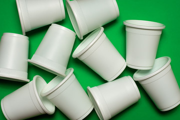 Disposable glasses from environmentally friendly materials on a green background. Biodegradable corn starch cookware. eco friendly. isolate