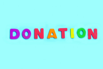 Word DONATION made of colorful letters on blue background.