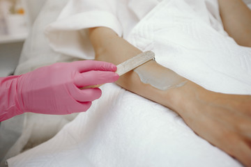 Hair removal. Gel for laser. Woman in a pink gloves.