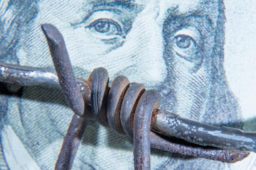Close up barbed wire against US Dollar bill as symbol of  bribery in politics, business, diplomacy.