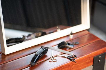 Obraz na płótnie Canvas Set of cutting tools for cutting hair at barbershop beard salon.Hair accessories such as Clippers and Comb on wooden desk table in a professional hairdresser barber.Stay home,Safe life.