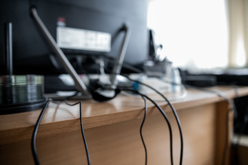 Concept of clutter in office. Unwound and tangled electrical wires under the table. 5S system of...