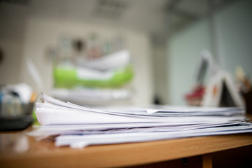 Pile of documents on desk stack up high waiting to be managed.