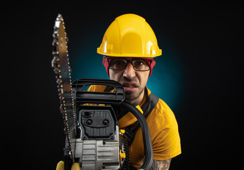 a guy in protective overalls with a chainsaw on a dark background