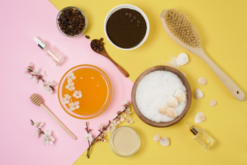 natural organic ingredients-sea salt, coffee scrub, honey and a hard body brush on a yellow background. home skin care for cellulite. concept of skin care, home Spa. the view from the top.