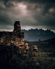 A vertical shot of a rock cliff under thunderhead dark sky