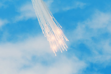 Falling burning flares of several meteorites of asteroids in the day cloudscape sky.