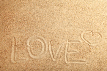 The inscription Love on the sandy background with copy space.