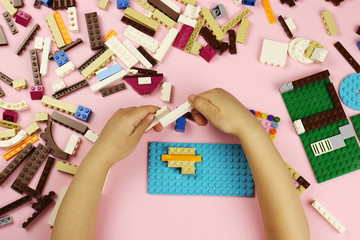 Child playing with colored blocks on a pink background