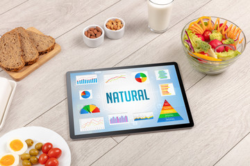 Organic food and tablet pc showing NATURAL inscription, healthy nutrition composition