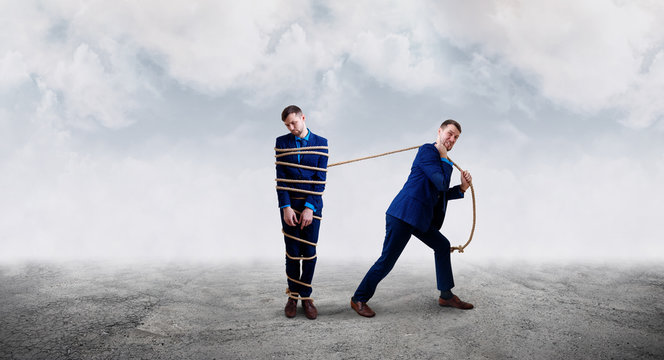 Angry businessman pulls tied himself with a rope.