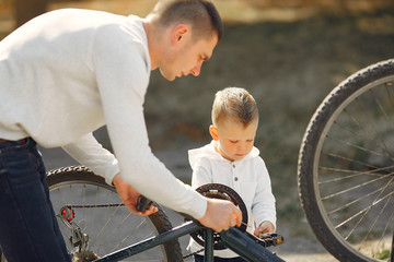 Obraz premium Family in a park. Father with son. People repare the bike.