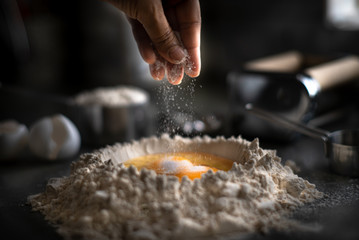 Process of making homemade wholewheat pasta in a kitchen with pasta sheet roller. Close up view. Dark photography