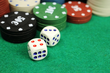 Casino chips and dice on a green felt table, selective focus