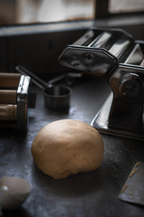 Process of making homemade wholewheat pasta in a kitchen with pasta sheet roller. Close up view. Dark photography