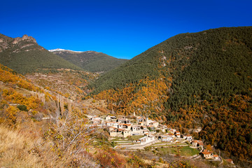 Fototapeta na wymiar Village in a valley surrounded by colorful vegetation and mountains on a beautiful sunny day