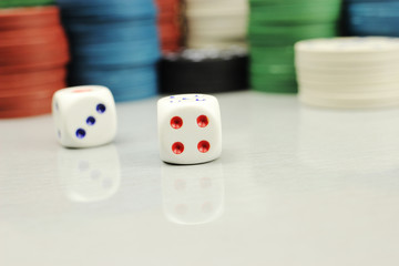 Casino chips and dice on a gray table, selective focus
