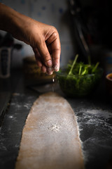 Process of making homemade wholewheat pasta in a kitchen with pasta sheet roller. Close up view. Dark photography