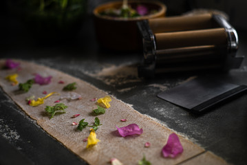 Process of making homemade wholewheat pasta in a kitchen with pasta sheet roller. Close up view. Dark photography