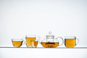 several tea glasses and a teapot on a glass table with a white background
