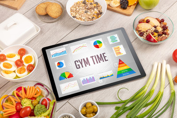 Organic food and tablet pc showing GYM TIME inscription, healthy nutrition composition