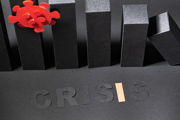 Close up abstract declining 3d bar chart made from black colored paper and letters stating word crisis. Red coronavirus shape attached. Over shades of gray. High angle.