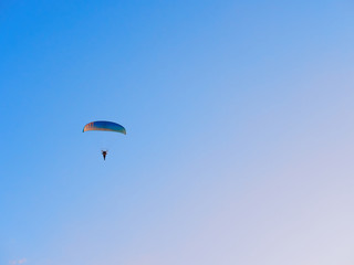 Paraglider flies on a paraglider over the city on a warm summer evening