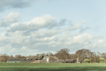 Barns and silos in sunny winter countryside with blue cloudy sky.